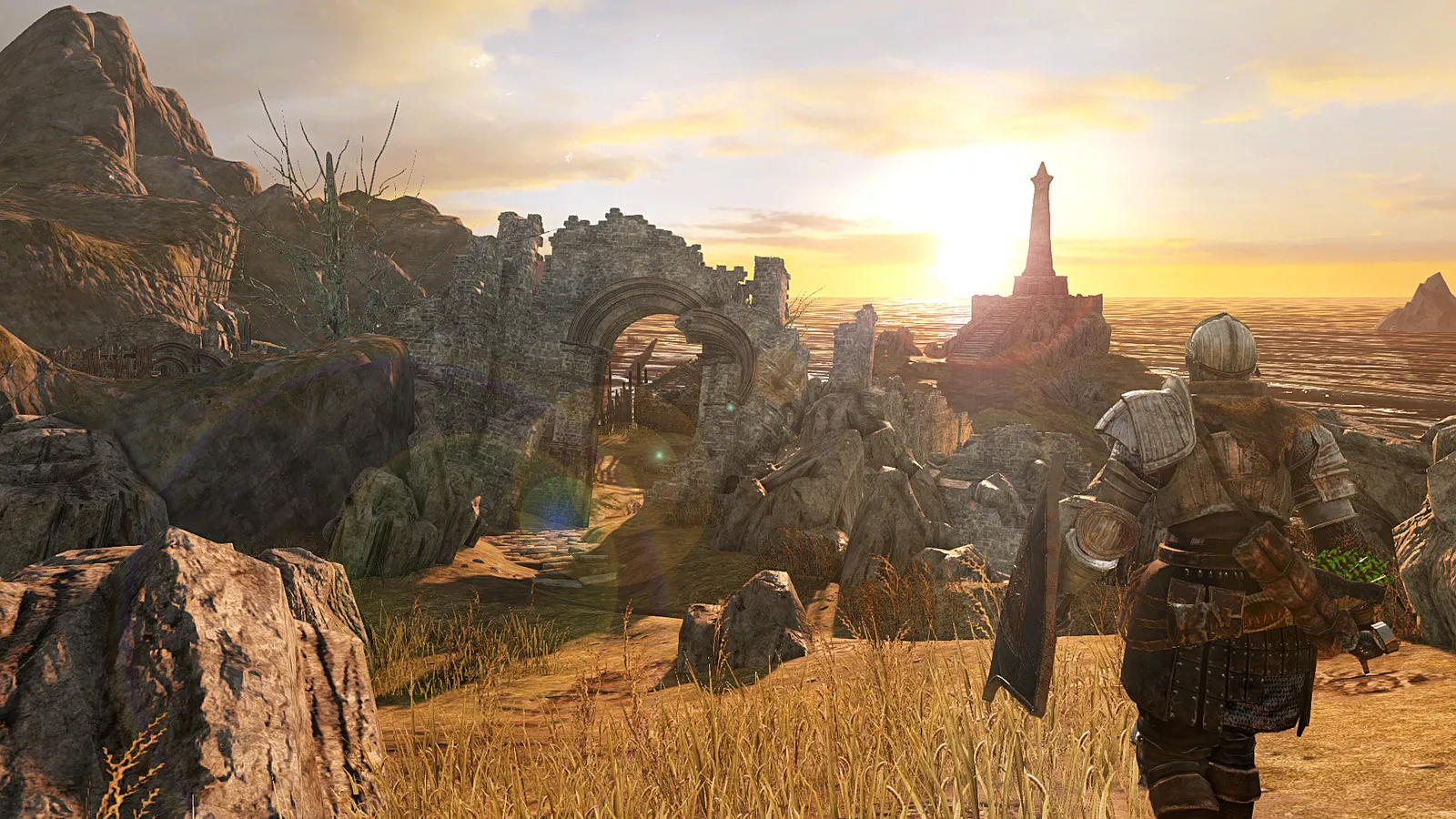 Personagem blindado com espada e escudo observa ruínas costeiras ao pôr do sol em Dark Souls II.
