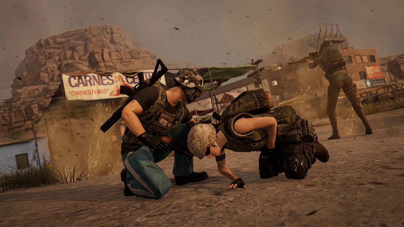 Jogador agachado auxilia companheiro caído enquanto outro atira em cenário desértico de PUBG: BATTLEGROUNDS.