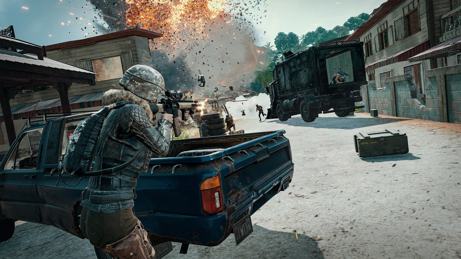Jogador armado usa uma picape como cobertura em rua com caminhão e explosão ao fundo em PUBG: BATTLEGROUNDS.